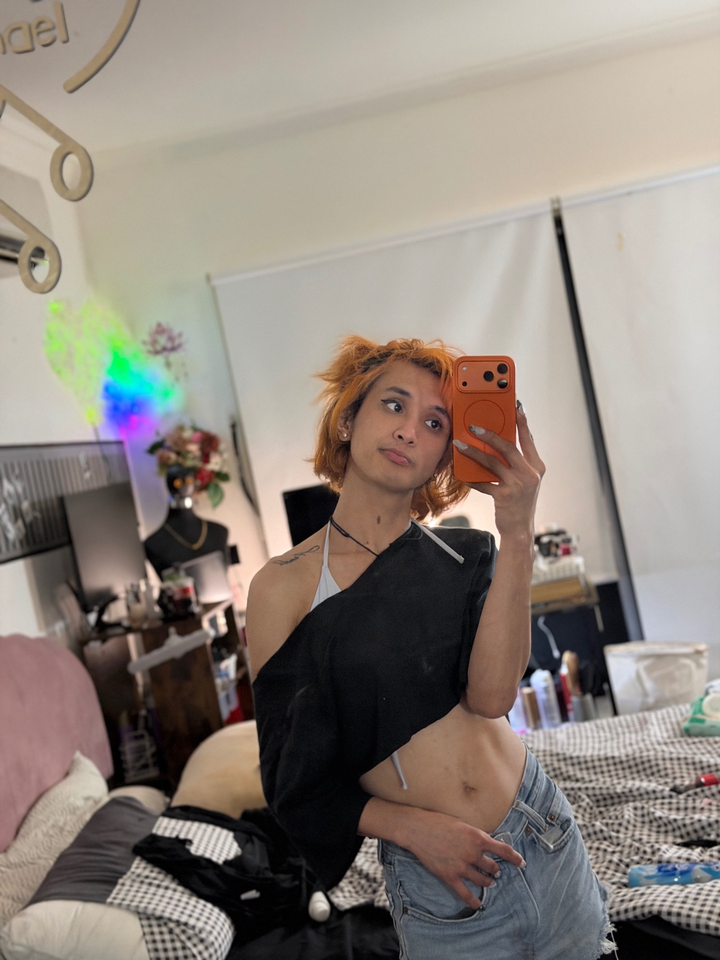 POR$CHA in a black one-shoulder top and jeans, bedroom mirror self-portrait