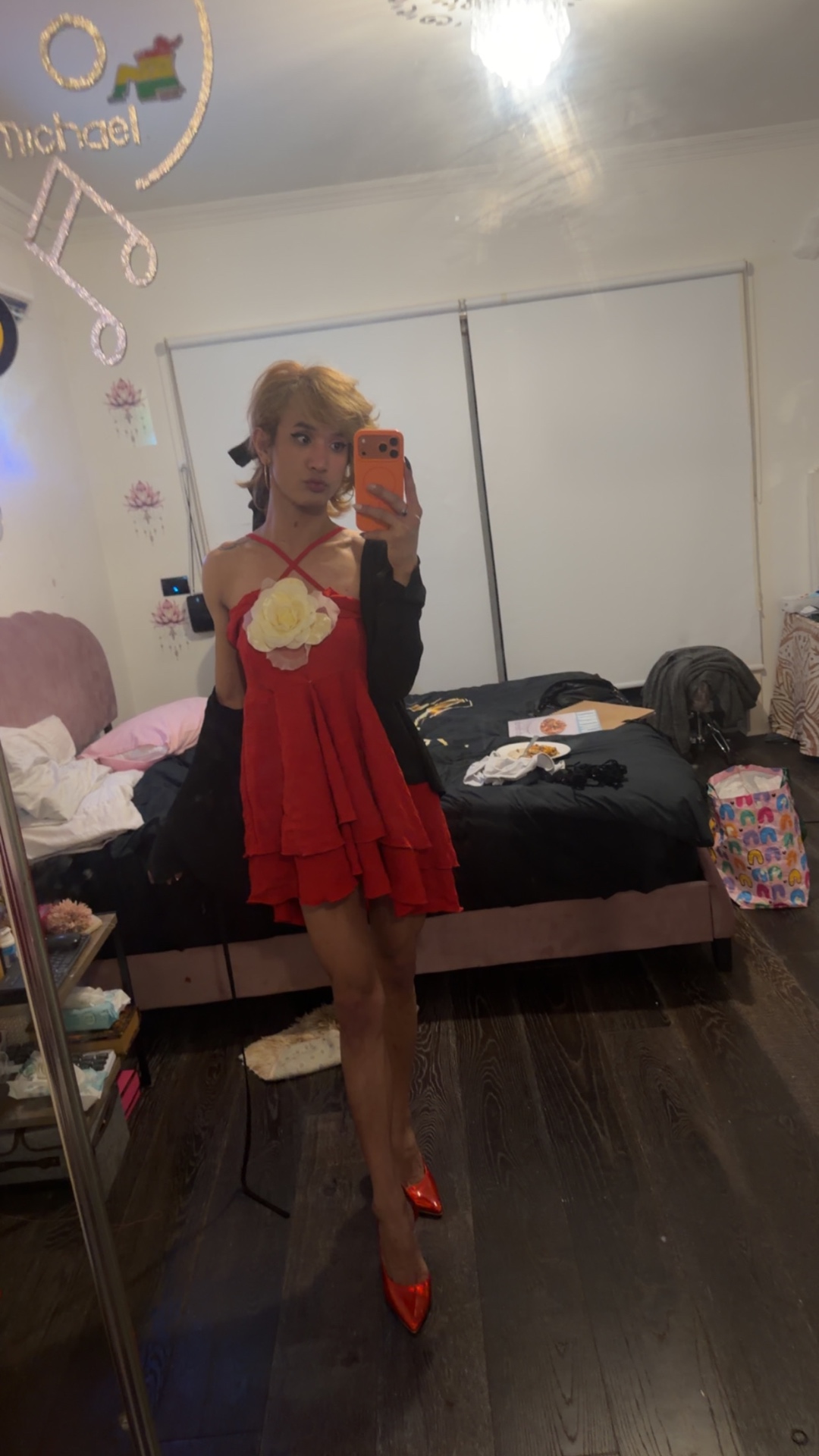POR$CHA in a red dress with a rose detail, bedroom mirror self-portrait