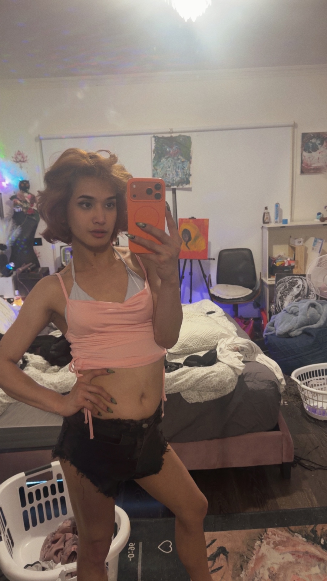 POR$CHA in pink top and black shorts, bedroom mirror self-portrait