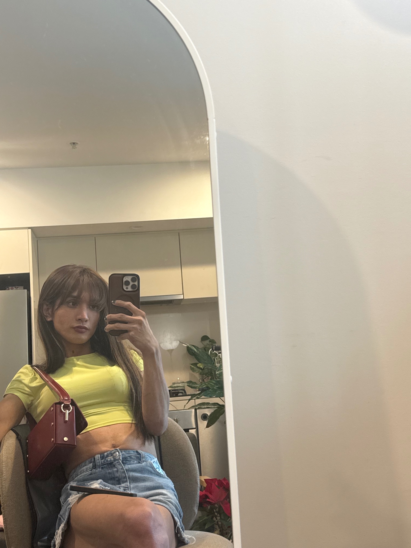 POR$CHA in neon yellow top and denim shorts, seated mirror self-portrait