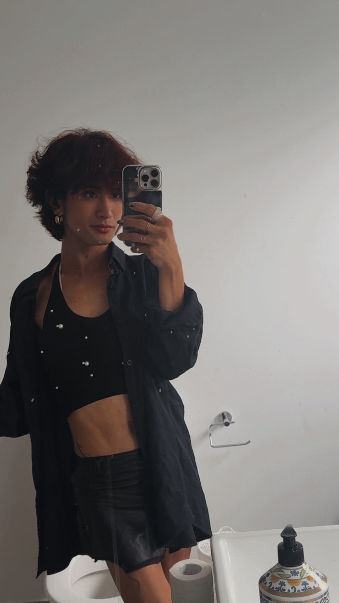 POR$CHA in a black cropped outfit, dim mirror self-portrait