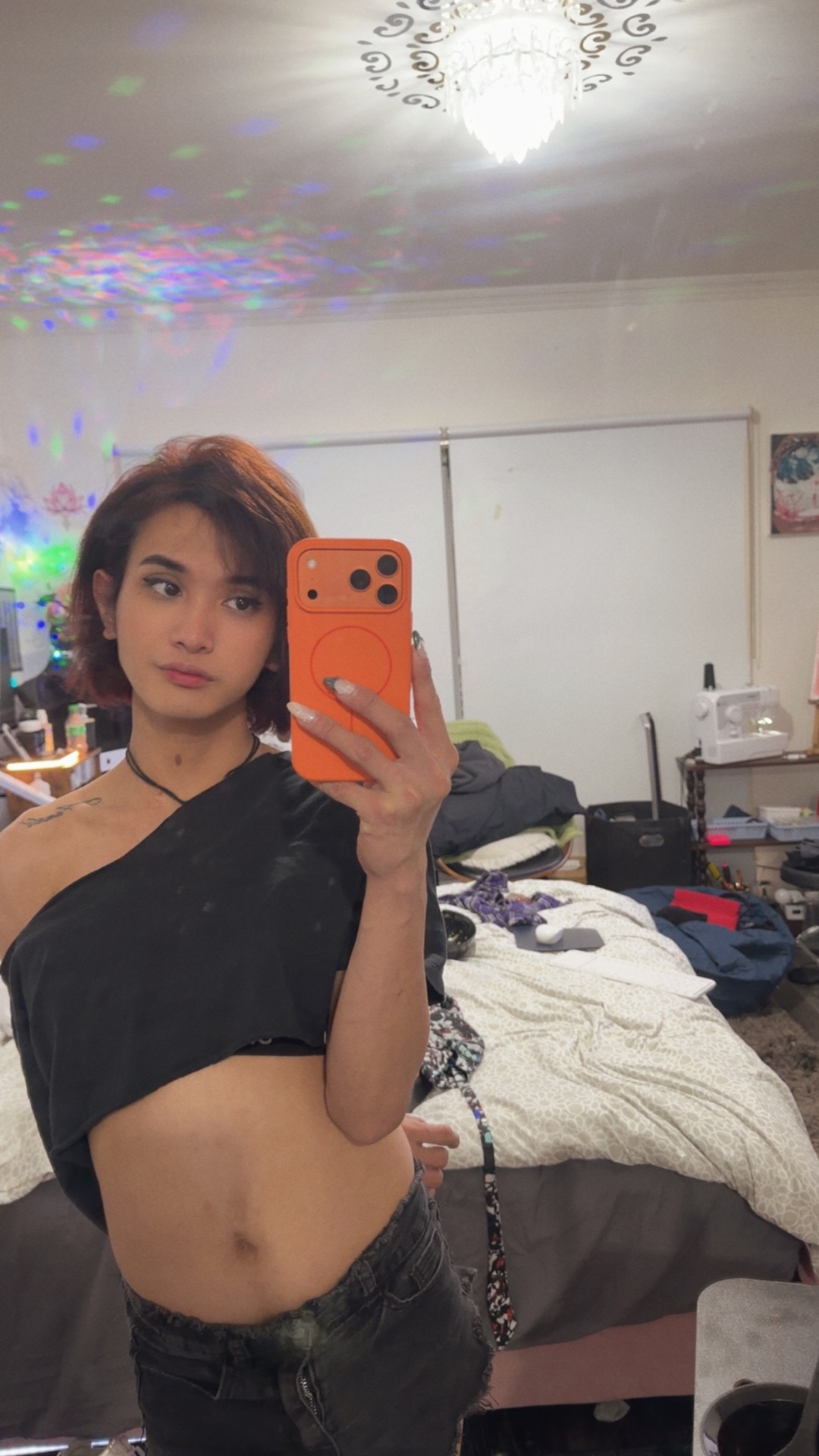 POR$CHA in a black crop top and dark jeans, bedroom mirror self-portrait