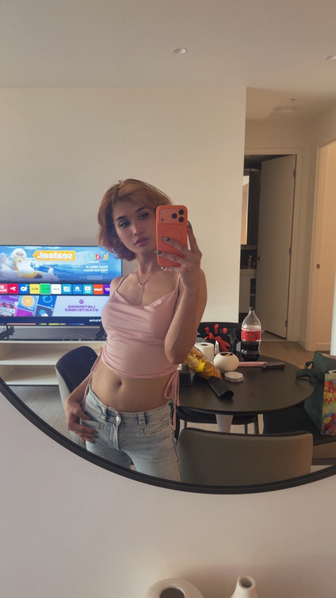 POR$CHA in pink top and jeans reflected in a round mirror