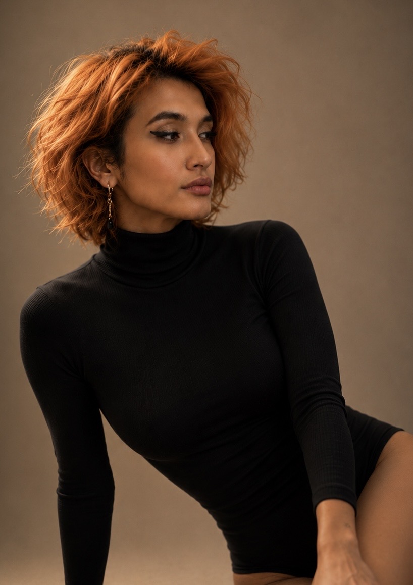 POR$CHA with tousled orange hair, winged eyeliner and black turtleneck